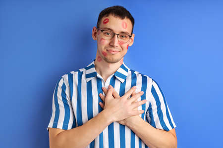 young caucasian  with kiss imprints isolated on blue background.の写真素材