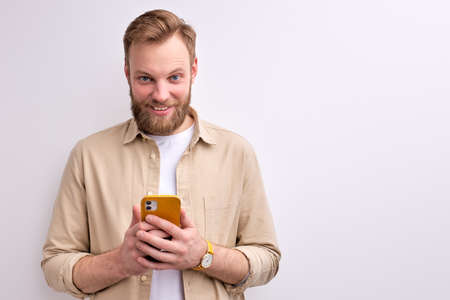Young Bearded Caucasian Guy Chatting With Someone On Smartphoneの写真素材