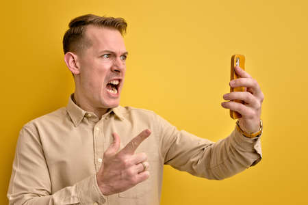 Side view Portrait Of Irritated Man Scolding Someone Via Smartphoneの写真素材