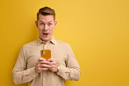 nice european man holding smartphone in hands creating social strategy influencer thinkingの写真素材