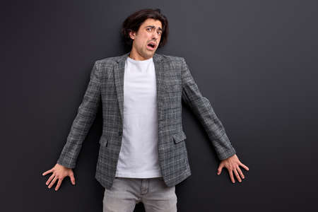 frightened man stand in shock, scared by something, leaned on black wallの写真素材