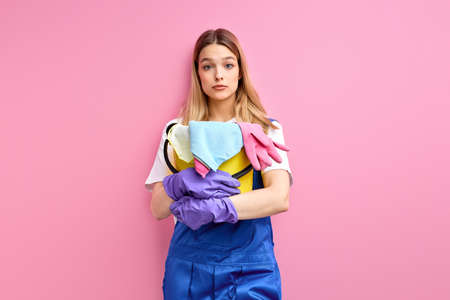 frightened woman with bucket and rags stands, does not know what to do with mess and dirtの写真素材