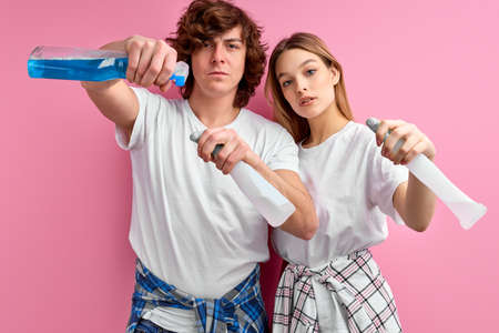 House cleaning. two cleaners on pink background, using sprays for cleaningの写真素材