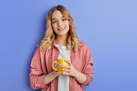 pretty teen girl drinking coffee or tea in morning before school or universityの写真素材