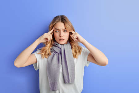 Thoughtful teenager girl concentrated on thoughts, isolated on blue backgroundの写真素材