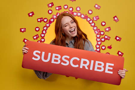 Portrait Of Redhead Female Holding Subscribe Title In Handsの写真素材