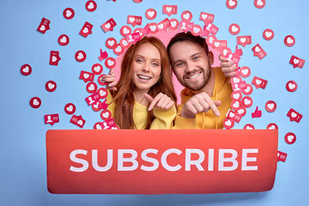 happy friends man and woman recommending to subscribe, pointing finger at titleの写真素材