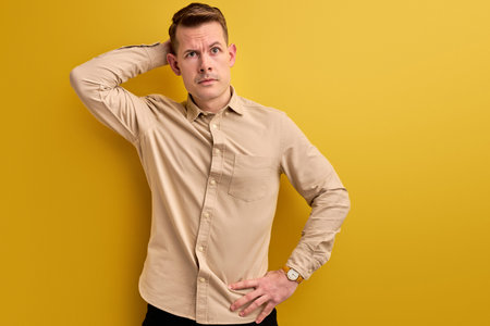 doubtful young caucasian man stand thinking, scratch back of head