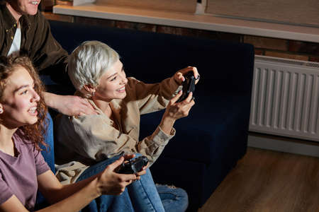 Young ladies playing game console at home at weekends in the evening, dressed casually, having leisure time. hobby, games, people lifestyle conceptの写真素材