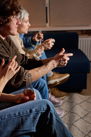 Cheerful joyful guys and ladies playing game console at home, enjoying rest, leisure time, as hobby...