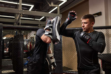 Professional mma fighter teaches self-defense tricks, showing it to young boxer. practice different techniques together. sport, workout concept. Side view copy spaceの写真素材