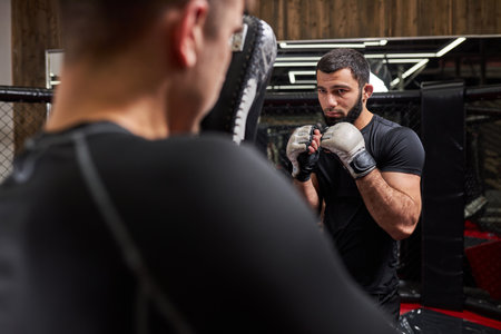 Strong Confident Fighter or Wrestler Training With Professional MMA Fighter At Gym In Ring, Preparing For Competition Together. Rear View on Manの写真素材