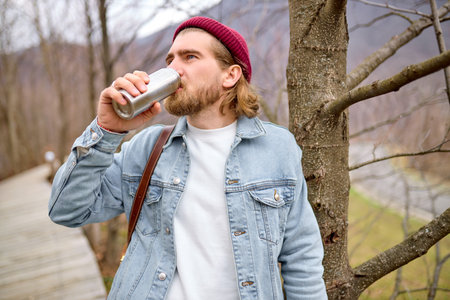 young handsome brutal bearded man traveling in the wild nature with , autumn or spring style,...