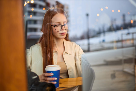 Concentrated young woman watching tutorial online on modern laptop device using wireless internet...
