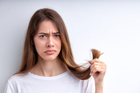 Upset frustrated woman holding hair in hands, want to cut them out, having split ends, look at...