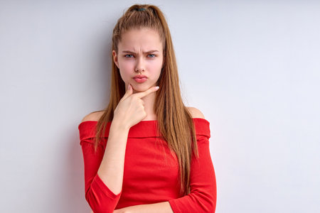 Puzzled perplexed young girl with distrustful face isolated on white studio wall, unbelieving suspicious girl looking at camera doubtful uncertain, caucasian female posing, copy space, bannerの写真素材
