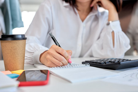 Cropped woman, close-up female hands holding pen making notes working in office, business concept....