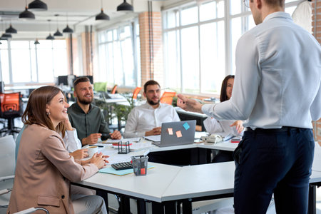 friendly nice business leader manager having talk, giving speech to colleagues. Young guy in formal...