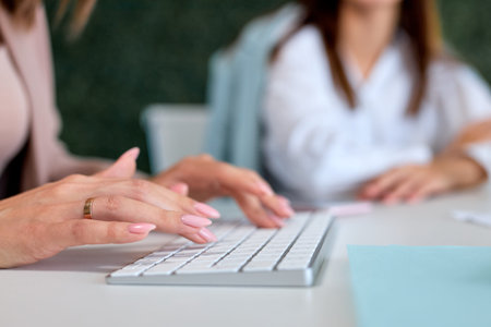 Business innovation and digital technologies.Young hardworking cropped businesswoman sitting in modern bright office and using computer. Corporate business concept, close-up female hands, copy spaceの写真素材