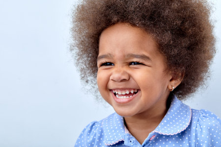 Close up portrait of little adorable African american child girl looking at side, having fun laughing isolated over white studio background. Copy space for advertisement. Human emotions, childrenの写真素材