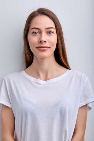 Calm Diligent Female With Natural Long Hair In Casual T-shirt Posing Smiling Isolated On White Studio Background, Portrait Of Lady With Natural Beauty Looking At Camera. Copy Spaceの写真素材