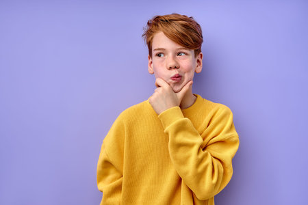 Let me think. Caucasian pensive clever redhead schooler in yellow shirt with puzzled serious...