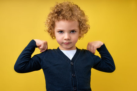 Look at my muscle, Im strong. Portrait of adorable little boy in T-shirt feeling powerful and...