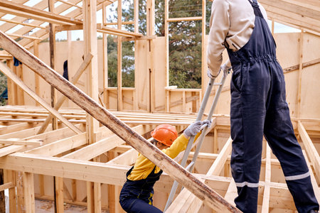 Cropped male contractor waiting helping female contractor comrade to climb the ladder, support and...