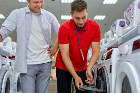 man consultant help customer with difficult decision, buy washing machine. Various choice. handsome...