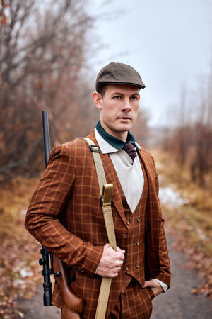 confident male hunter is going to hunt, dressed in brown stylish suit and hat. handsome good-looking...