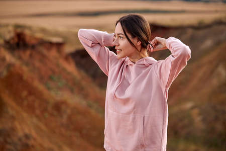 Attractive lady is preparing for training outdoors, looking at side in contemplation, getting ready for jogging, in pink sportive hoodie. active woman is motivated and concentrated on sportの写真素材
