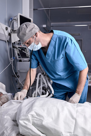 Experienced male doctor putting stethoscope to senior patient, checking the heartbeat. at nursing...