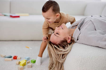 Caucasian Mother and child at home in living room. Mom and kid boy playing in sunny cozy room. Parent and little kid relaxing at home. Family having fun together. At weekends, leisure timeの写真素材