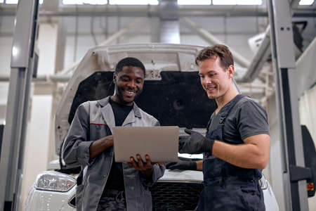 Services car engine machine concept, car mechanic repairmen checking car engine with using computer diagnostics while repairing, car service and maintenance. team work of diverse menの写真素材