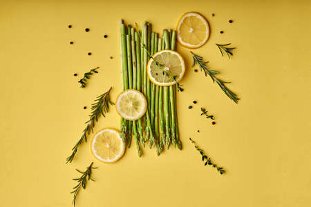 Asparagus. fresh green asparagus close-up with slice of lemon isolated on yellow background. Healthy vegetarian food, nutrition. flat lay, copy spaceの写真素材