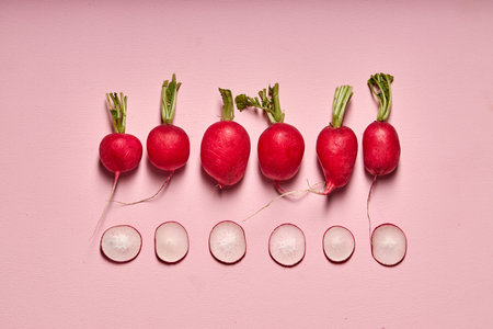 Red radish and its slices isolated on pink wall background. top view. creative shot of bright fresh...