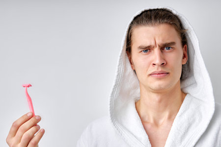 Handsome young man in bathrobe isolated.close-up Portrait of confused strong muscular man with razor...