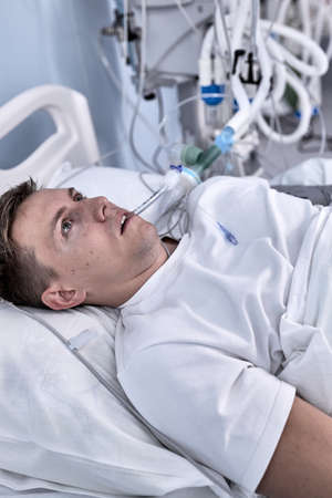 young injured man lying in bed hospital room resting from pain looking in bad health condition after suffering accident in health care conceptの写真素材