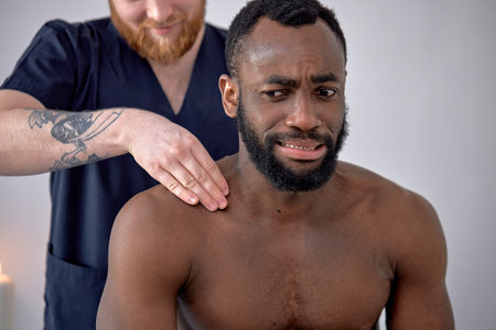 cropped caucasian Spa therapist making relaxing massage for handsome middle aged black man, rubbing...
