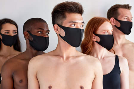 health, quarantine and pandemic. young people wearing protective medical masks for protection from virus omicron covid-19. diverse men and women posing isolated over white, looking at sideの写真素材