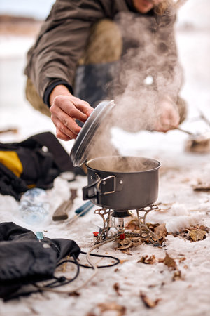 cropped unrecognizable man preparing food in winter forest. Bushcraft, travel, adventure, tourism...