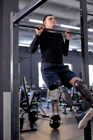 young motivated serious man building upper body strength, hanging on bar, fitness, cross fit, full...