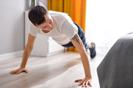 active handsome Caucasian guy with leg prosthesis artificial legs engaged in sport, doing exercises...