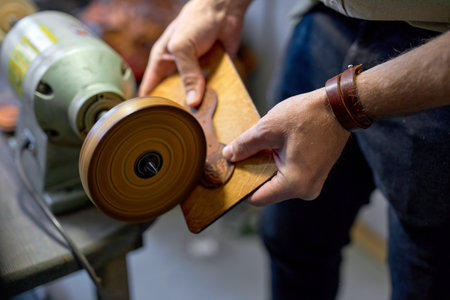 man smoothing and polishing leather cut, close up cropped side view shot, guy smooths the surface of wallet, belt and makes it shinierの写真素材