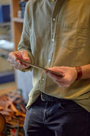 young man in greeb shirt and jeans holding cut leather, piece of material,closwe up side view...