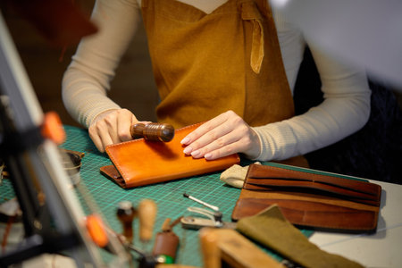 young talented woman polishing edges od wallet with slicker, burnisher creating sewing leather handmade wallet leathercraft, close up cropped shot. free time, spare time, lifestyleの写真素材