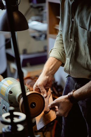 man using hand-crafted, high-quality burnisher at workplace. close up side view shot.Leather Craft
