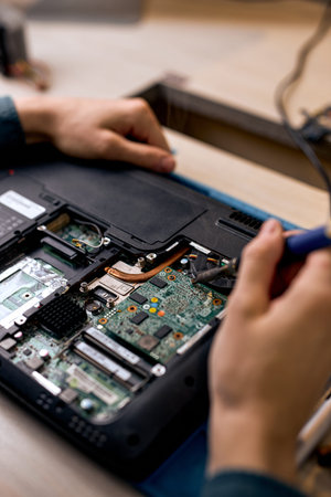 Hand technician repairing broken laptop notebook computer with tools, alone, at workshop....