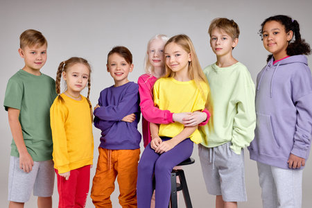 multiethnic children in casual colourful clothes stand in a row and smile, isolated white background, diverse classmates look at camera friendshipの写真素材