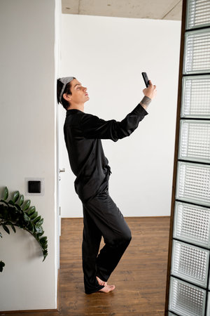 attractive brunette guy looking for wi-fi, internet conncection at home, full length side view shot,...